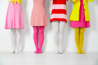 Women wearing colorful tights near white wall, closeup