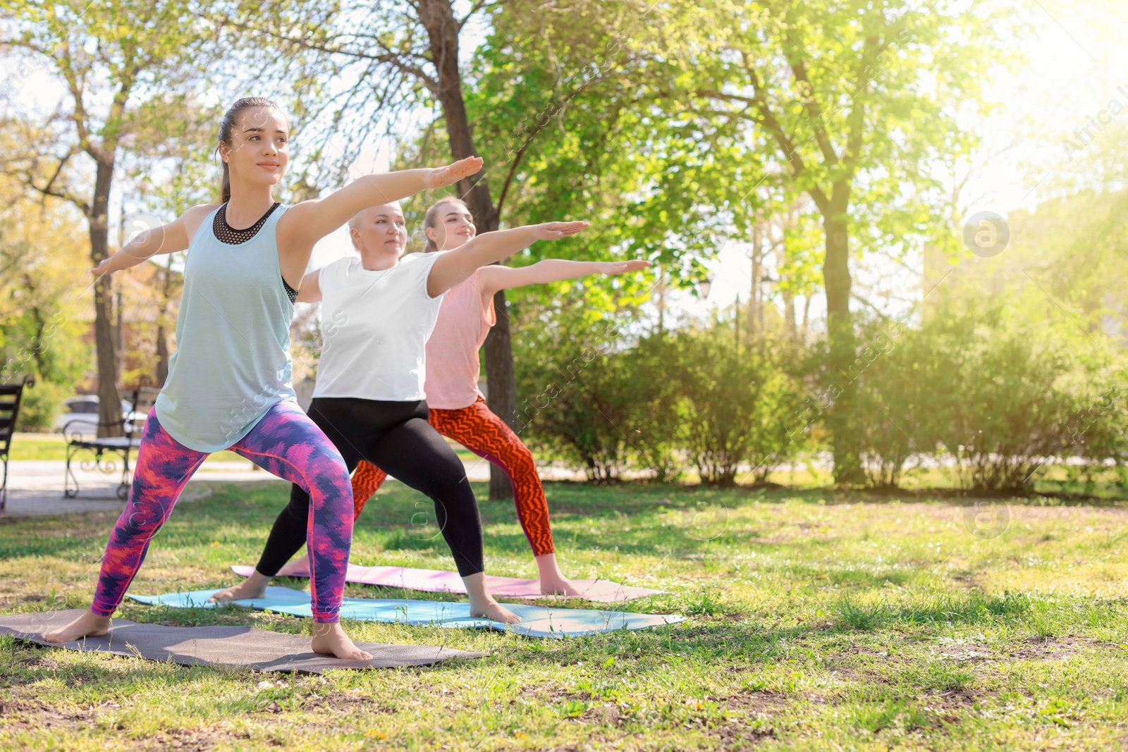 Photo of Group of women practicing yoga in park on sunny day