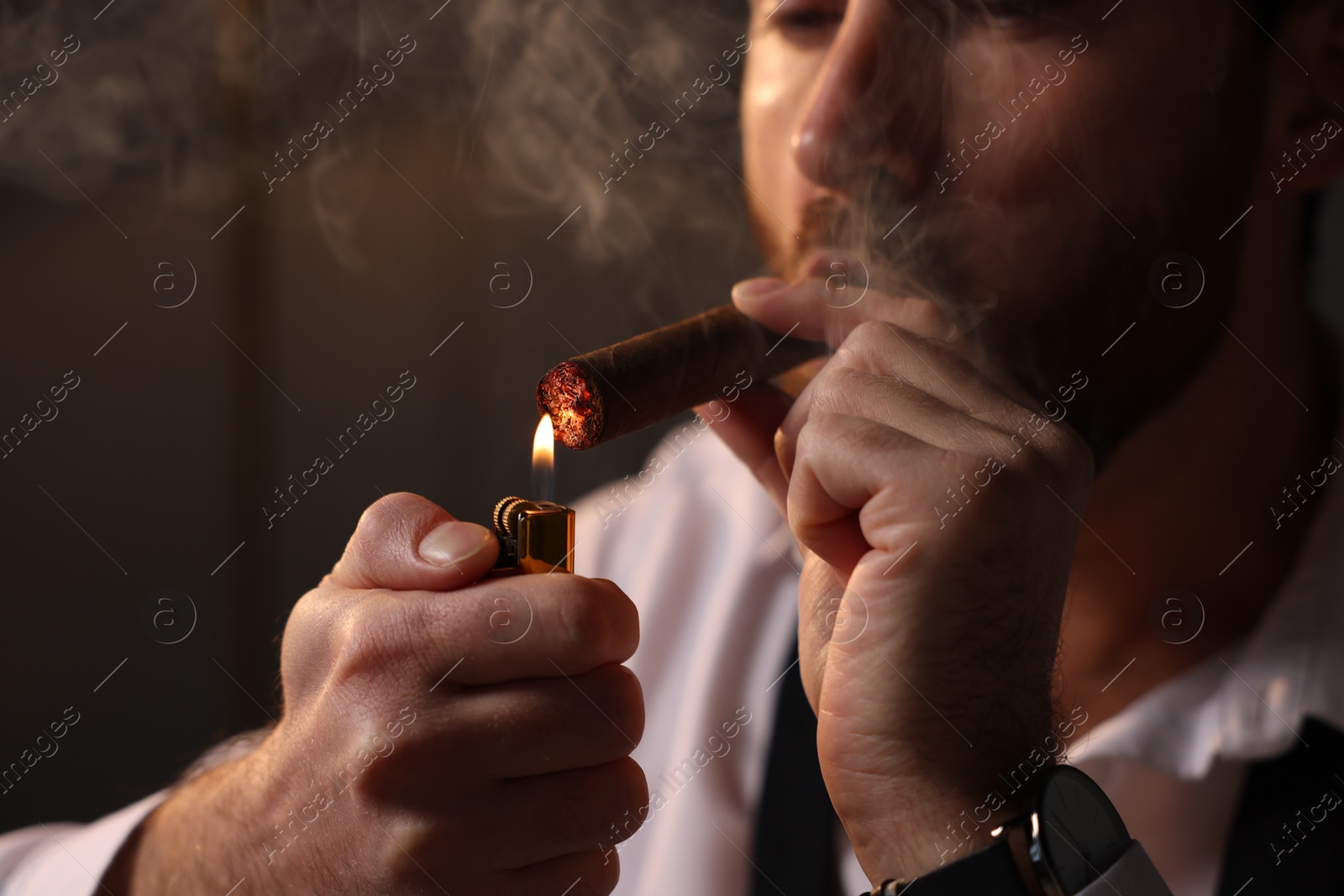 Photo of Man lightning cigar at home, closeup view