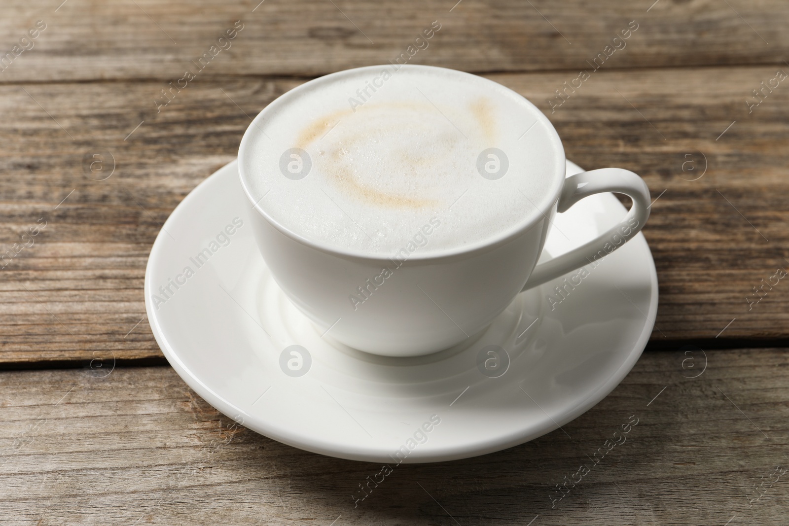 Photo of Tasty cappuccino in coffee cup on wooden table, closeup
