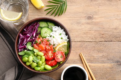 Poke bowl with salmon, edamame beans and vegetables on wooden table, flat lay. Space for text