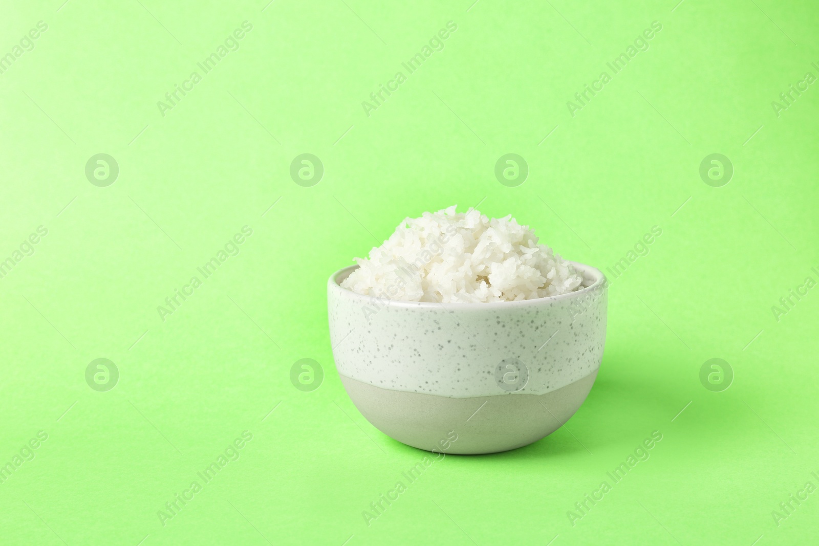 Photo of Bowl of boiled rice on color background. Space for text