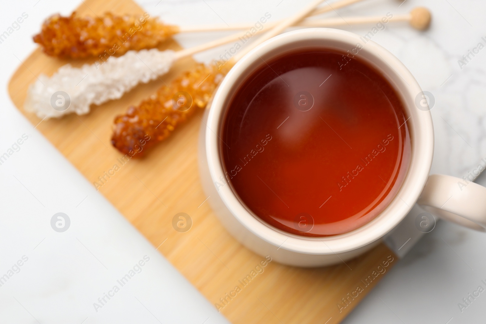 Photo of Sticks with sugar crystals served to tea on white table, top view