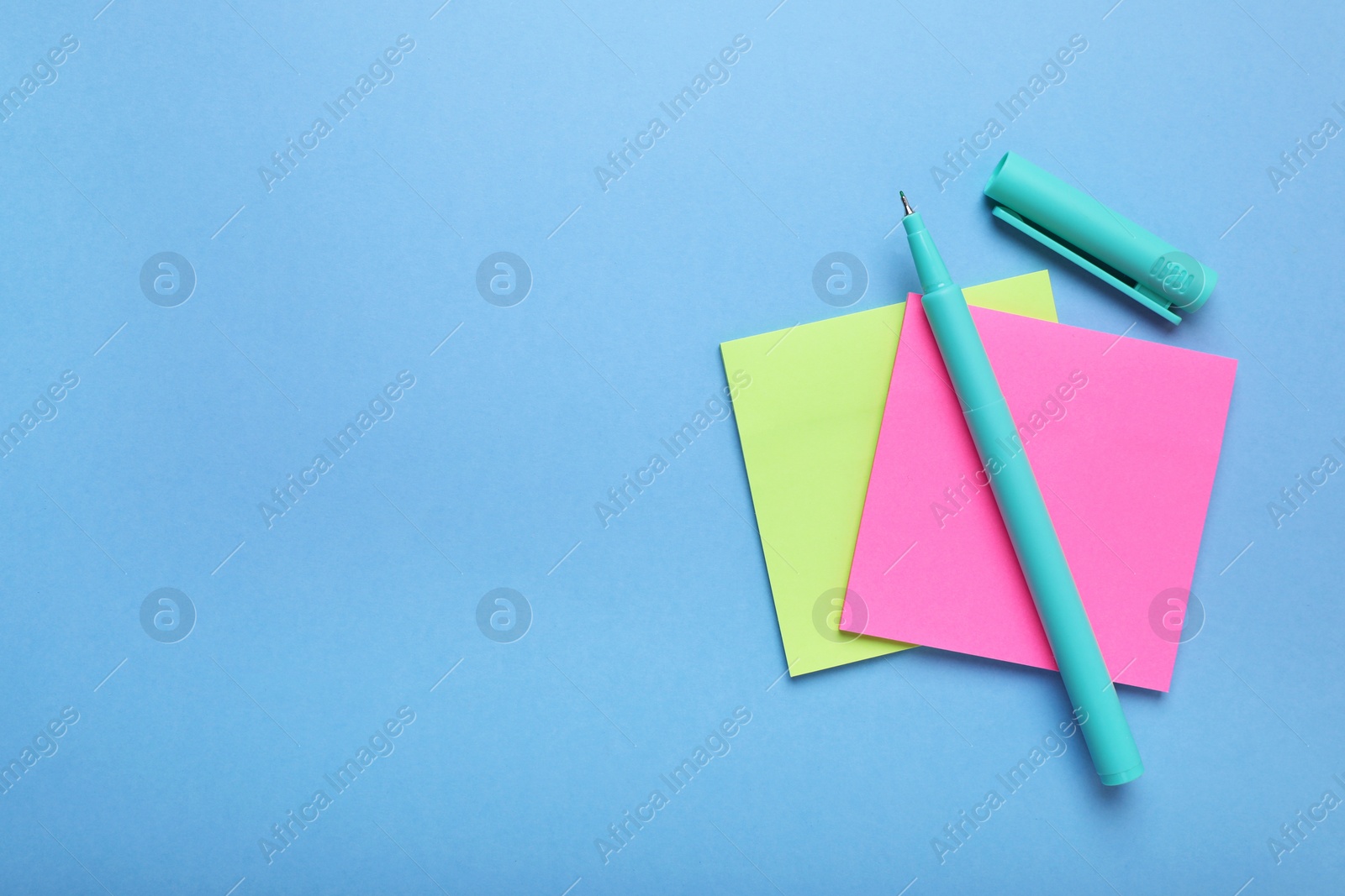 Photo of Paper notes and color marker on light blue background, top view. Space for text