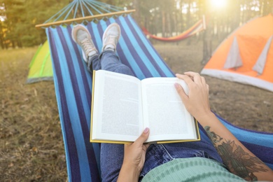Photo of Woman with book resting in comfortable hammock outdoors, closeup