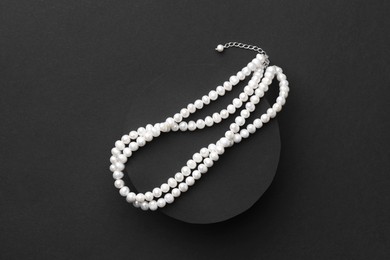 Photo of Elegant pearl necklace on black background, top view