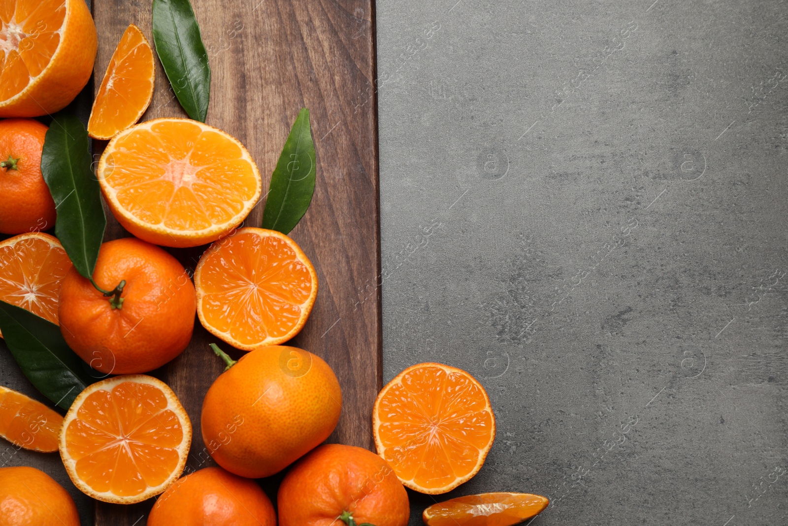 Photo of Fresh ripe tangerines and space for text on dark grey table, flat lay. Citrus fruit