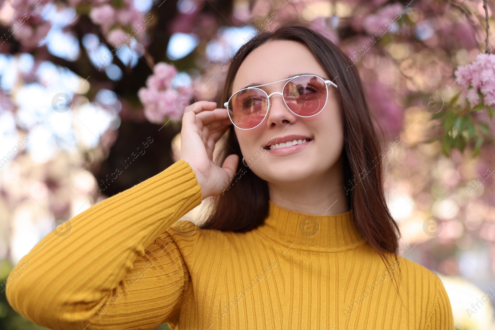 Photo of Beautiful woman in sunglasses near blossoming tree on spring day