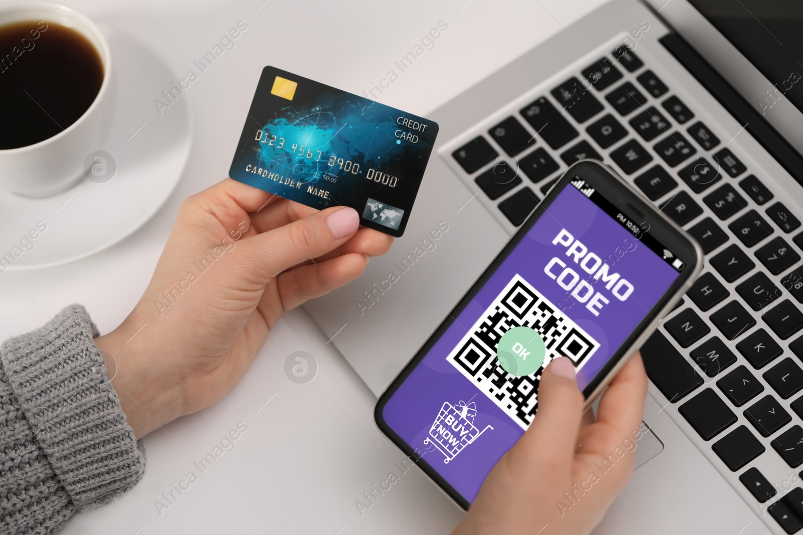 Image of Woman holding credit card and smartphone with activated promo code in online shopping app at white table, closeup