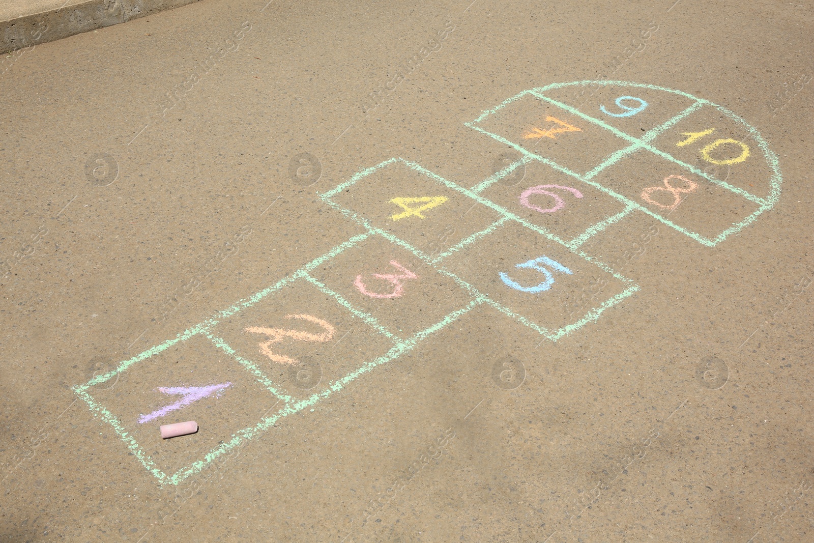 Photo of Hopscotch drawn with colorful chalk on asphalt outdoors