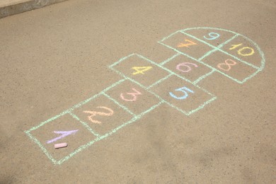 Hopscotch drawn with colorful chalk on asphalt outdoors