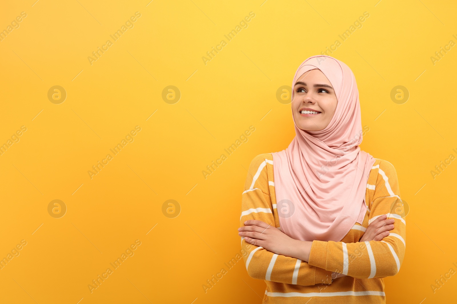 Photo of Portrait of Muslim woman in hijab on orange background, space for text