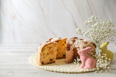 Delicious Italian Easter dove cake (traditional Colomba di Pasqua) and festive decor on white wooden table, space for text