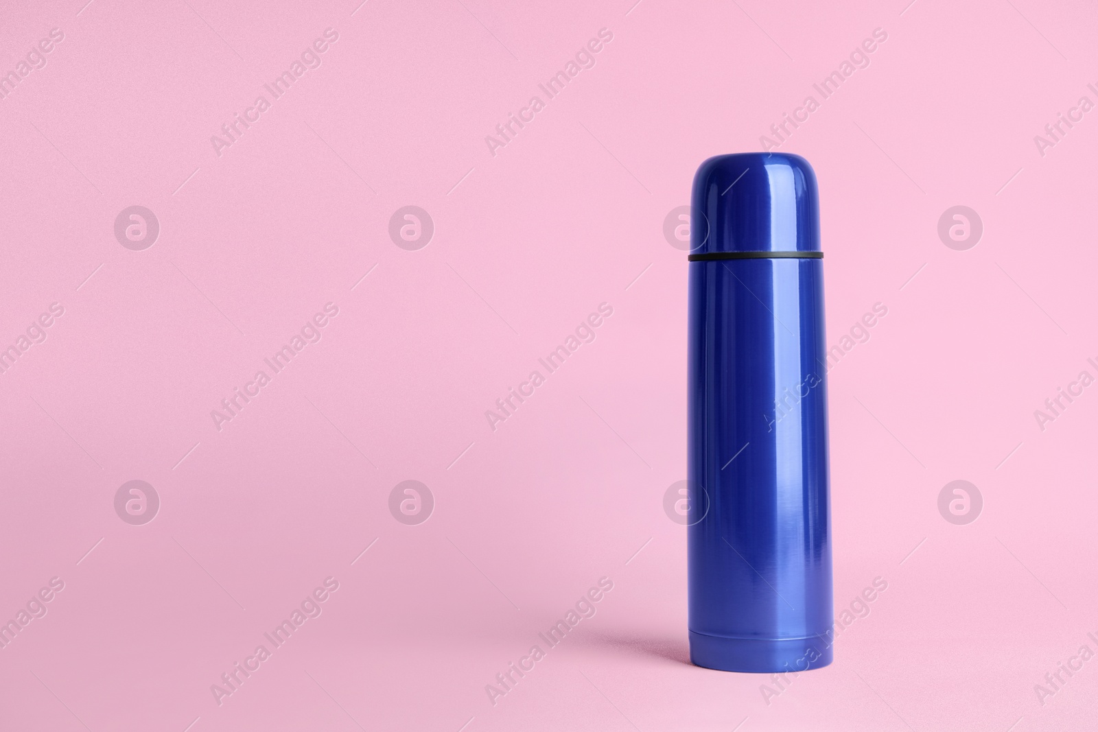 Photo of Stylish thermo bottle on pink background, space for text