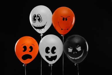 Photo of Spooky balloons for Halloween party on black background