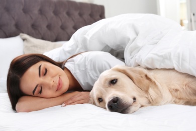 Young woman and her Golden Retriever dog on bed at home