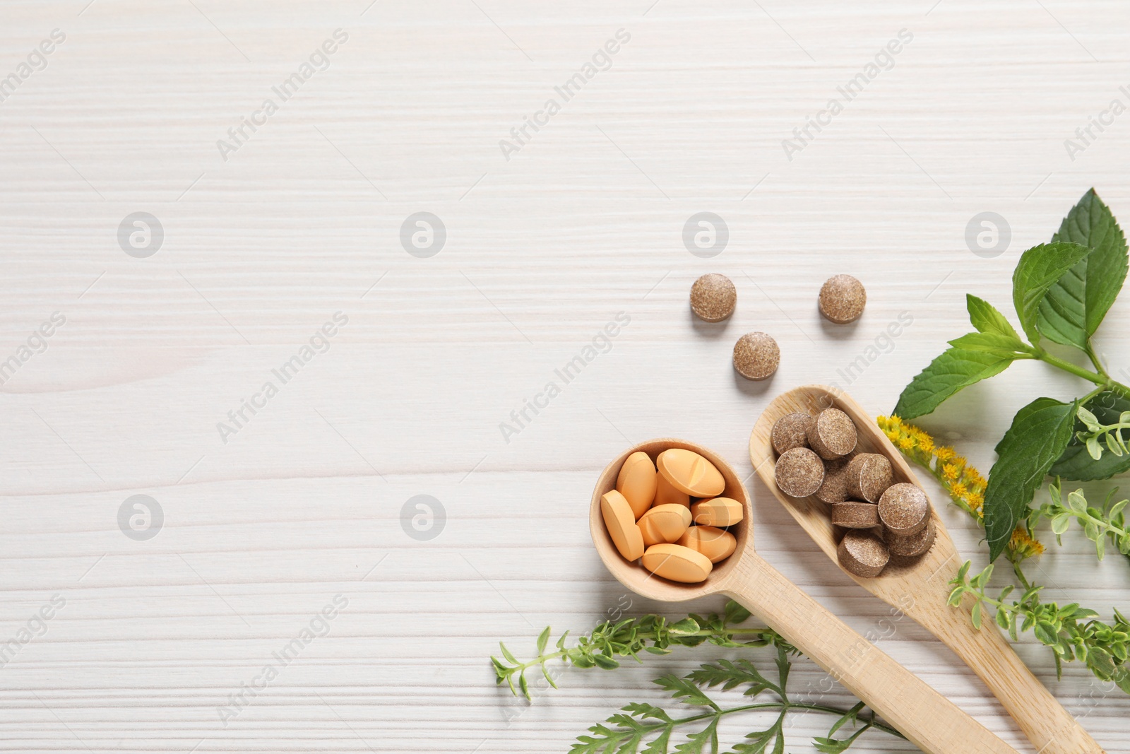 Photo of Different pills and herbs on white wooden table, flat lay with space for text. Dietary supplements