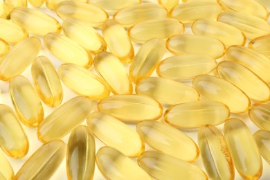 Photo of Many yellow vitamin capsules on white background, closeup