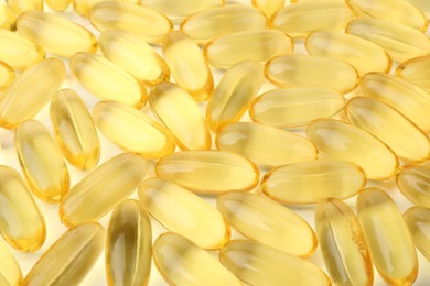 Many yellow vitamin capsules on white background, closeup