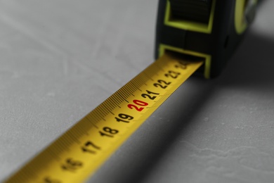 Photo of Tape measure on light grey background, closeup. Construction tool