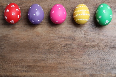 Photo of Colorful eggs on wooden background, flat lay with space for text. Happy Easter