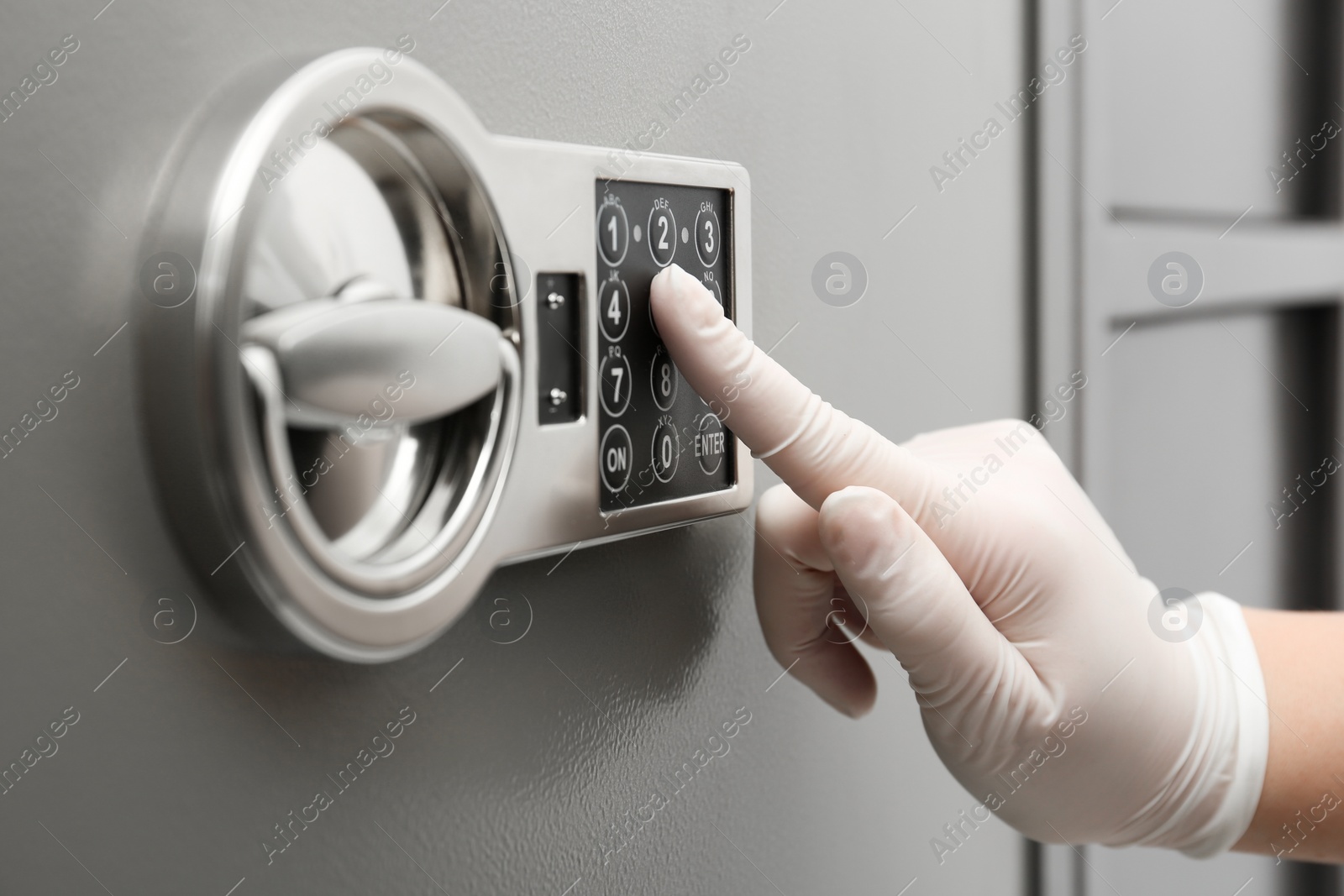 Photo of Woman in gloves entering code on keypad of modern safe, closeup