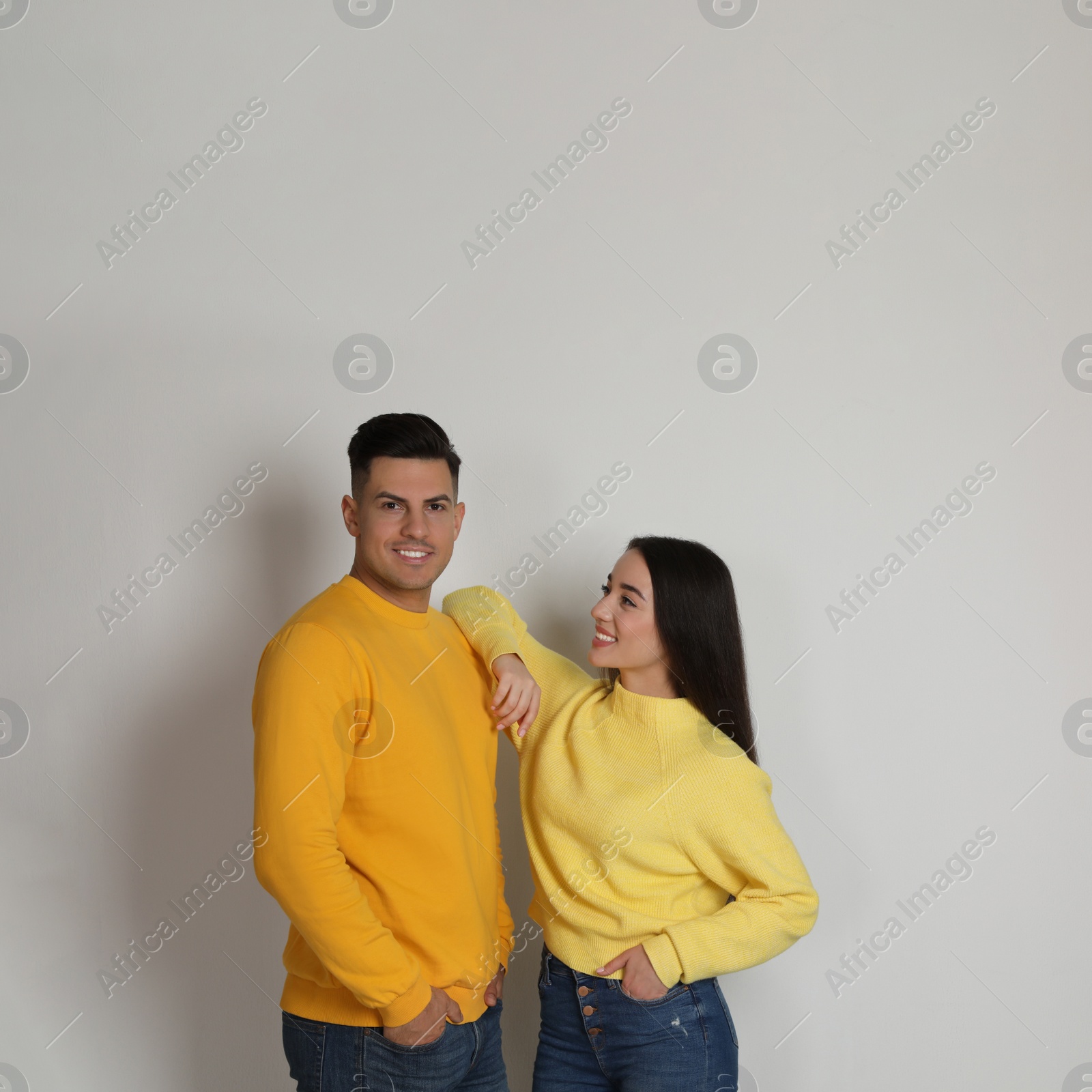 Photo of Happy couple wearing yellow warm sweaters on white background. Space for text