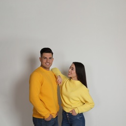 Photo of Happy couple wearing yellow warm sweaters on white background. Space for text