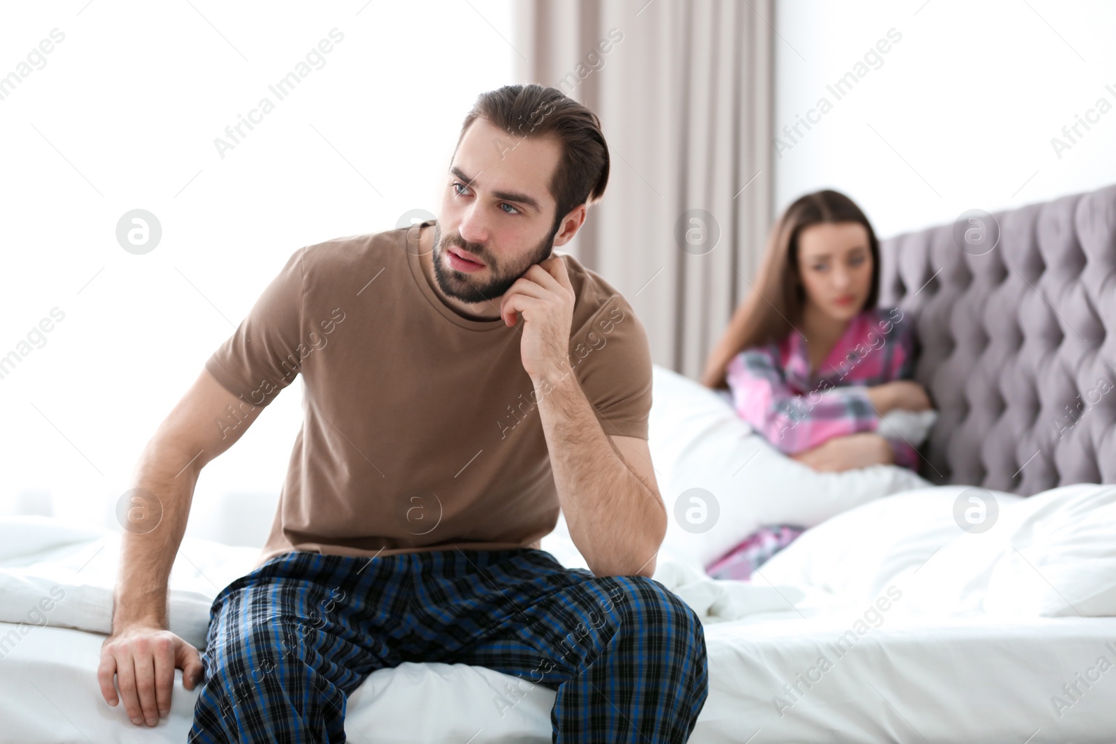 Photo of Young couple ignoring each other after having argument in bedroom