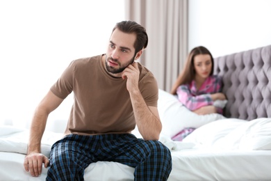 Photo of Young couple ignoring each other after having argument in bedroom