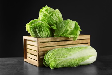 Photo of Fresh ripe Chinese cabbages and wooden crate on grey table