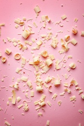 Photo of White chocolate curls on color background, top view