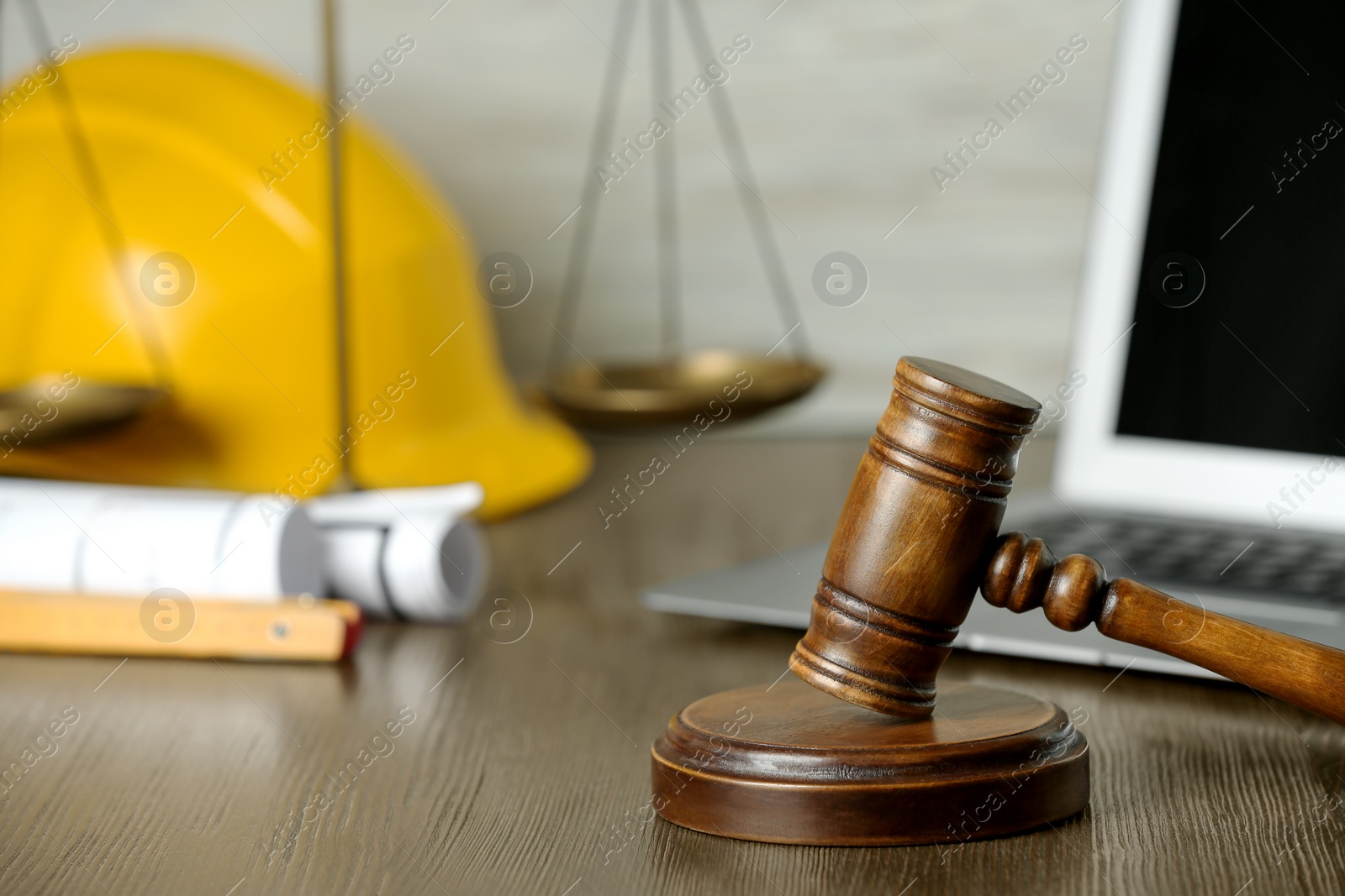 Photo of Construction and land law concepts. Judge gavel, scales of justice, protective helmet, drawings with laptop on wooden table