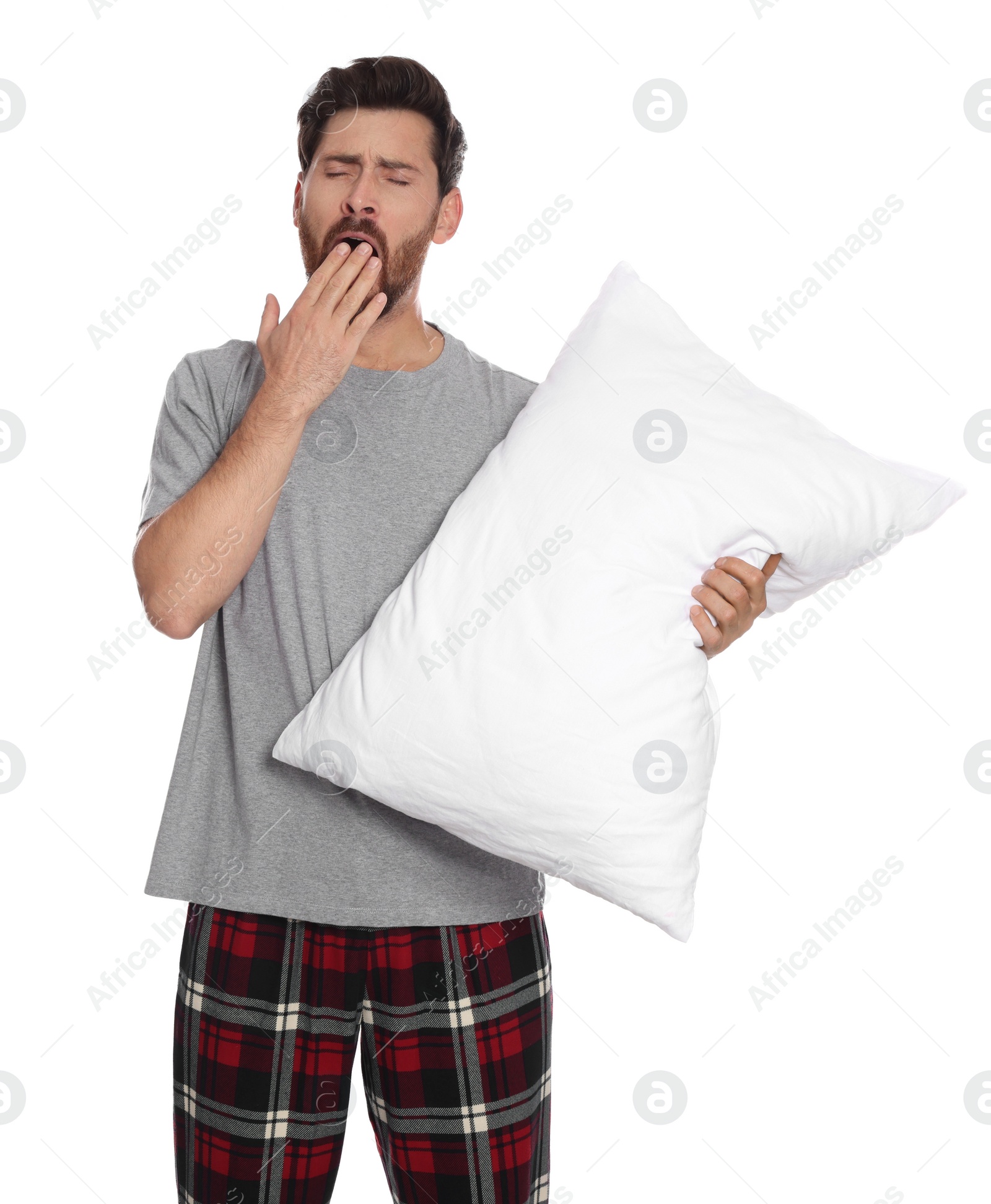 Photo of Tired man with pillow yawns on white background