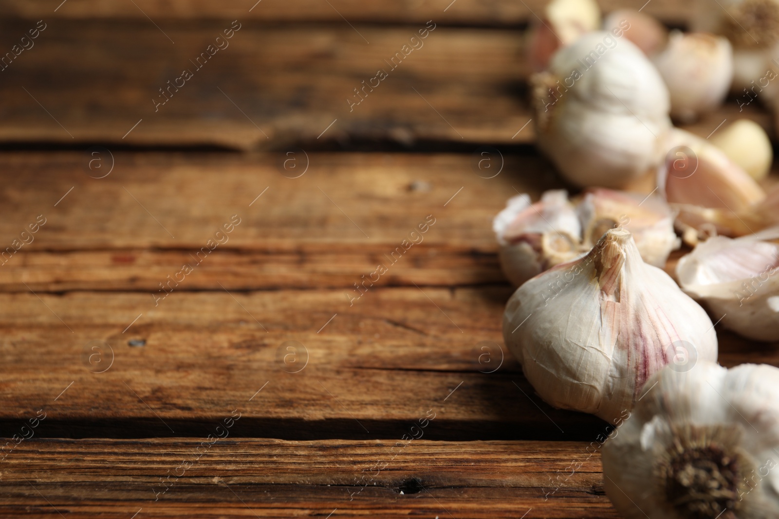 Photo of Fresh organic garlic on wooden table, closeup. Space for text