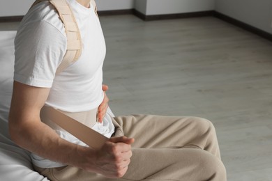 Closeup view of man with orthopedic corset sitting in room