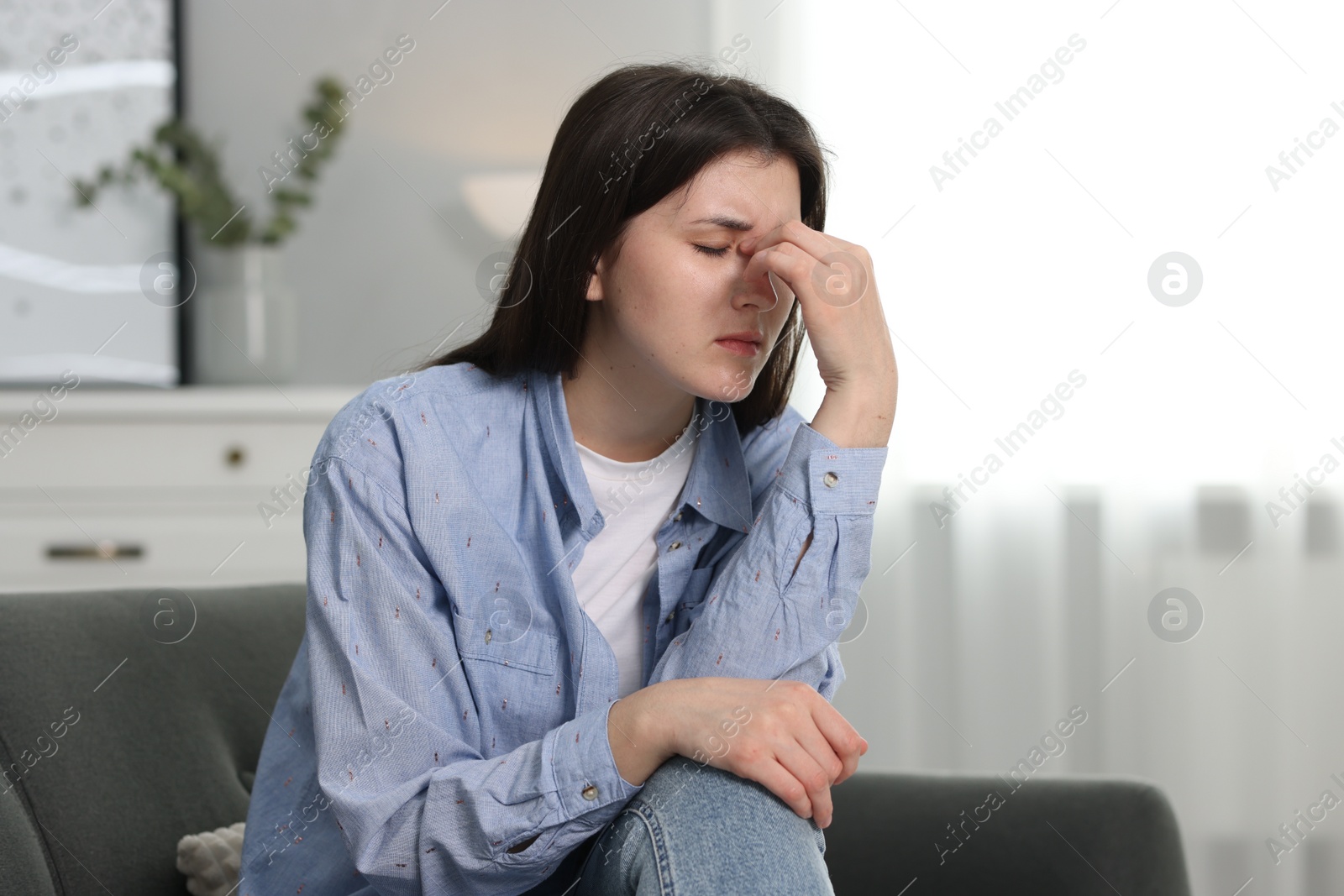 Photo of Overwhelmed woman sitting on sofa at home