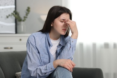 Photo of Overwhelmed woman sitting on sofa at home