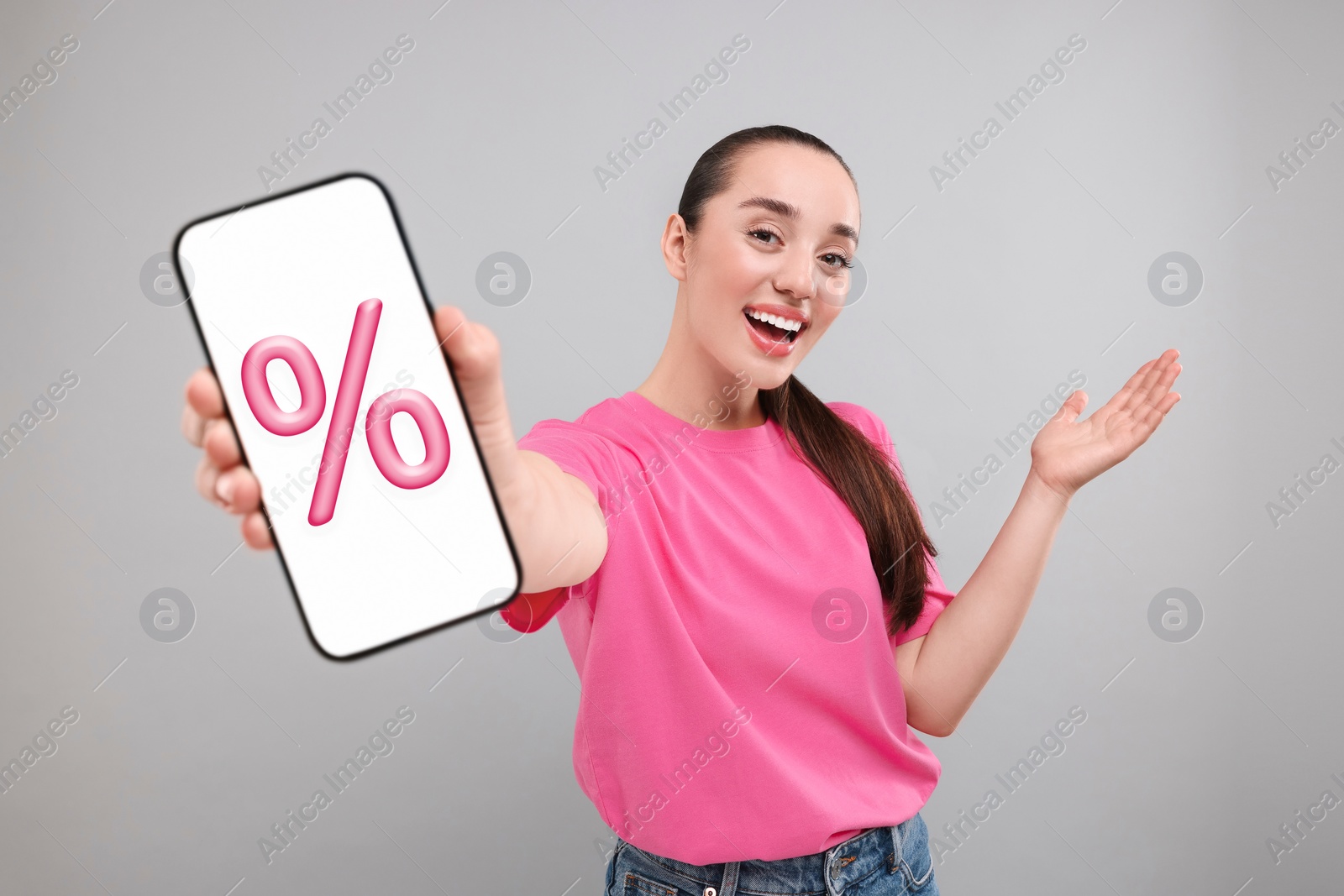 Image of Discount, offer, sale. Woman showing mobile phone with percent sign on screen, grey background