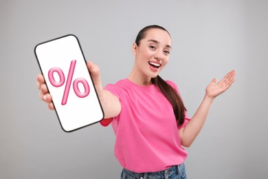 Image of Discount, offer, sale. Woman showing mobile phone with percent sign on screen, grey background