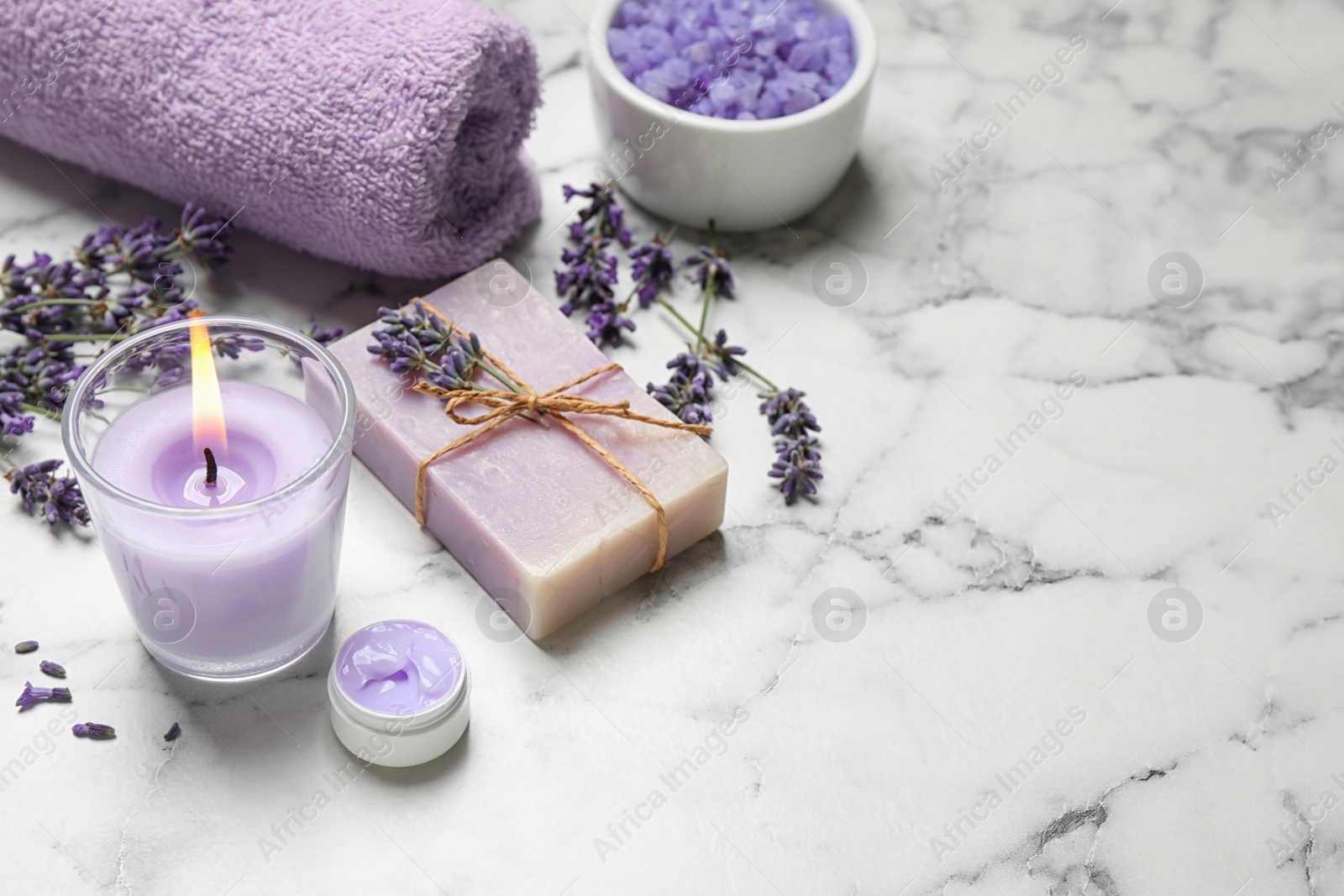 Photo of Cosmetic products and lavender flowers on white marble table. Space for text