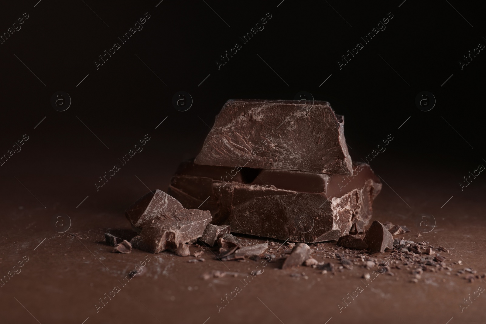 Photo of Pieces of dark chocolate on brown table