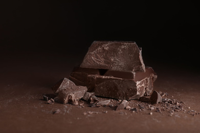 Photo of Pieces of dark chocolate on brown table