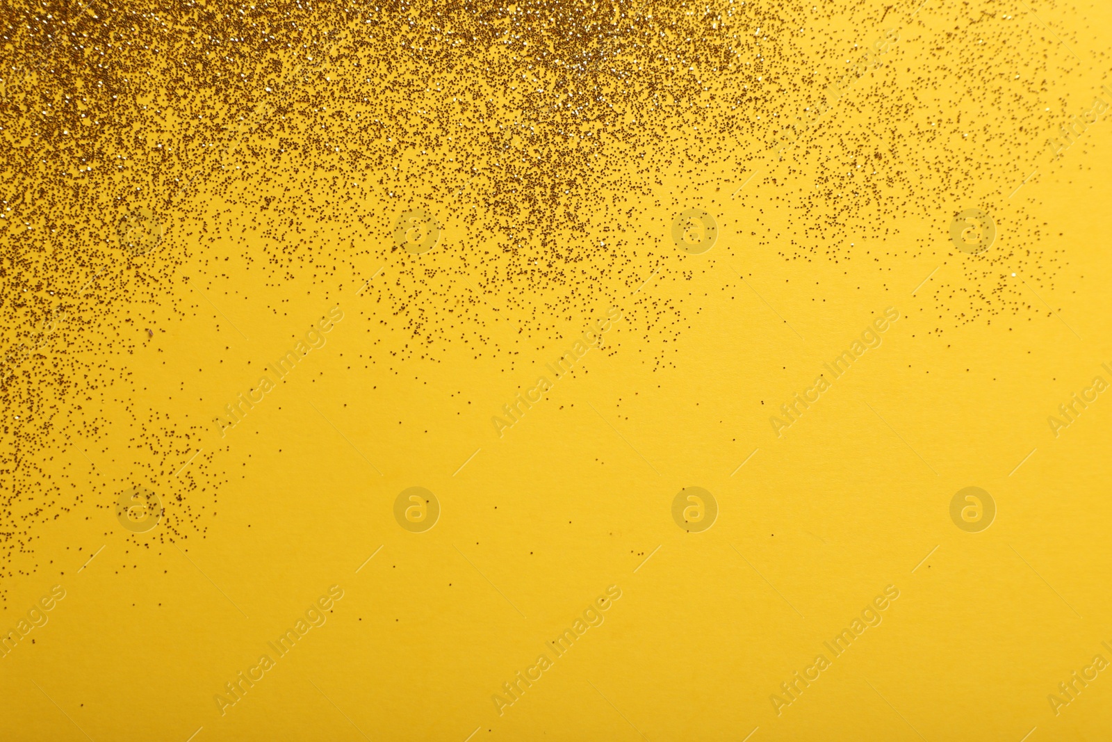 Photo of Shiny golden glitter on yellow background, top view. Space for text