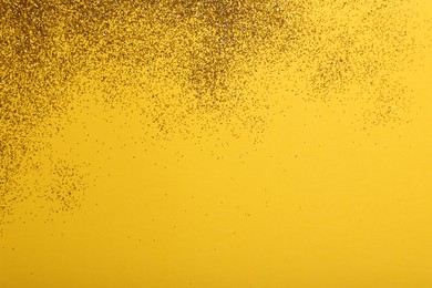 Shiny golden glitter on yellow background, top view. Space for text