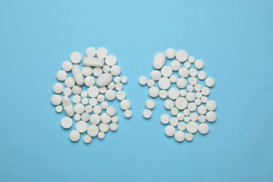 White pills in shape of kidneys on light blue background, flat lay