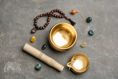 Photo of Flat lay composition with golden singing bowl on grey stone table. Sound healing