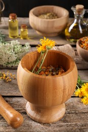 Photo of Mortar, pestle and calendula flowers on wooden table. Medicinal herbs