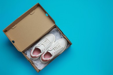 Photo of Comfortable shoes in cardboard box on light blue background, top view. Space for text