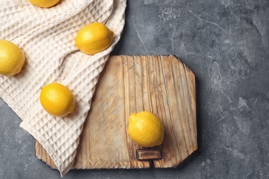 Photo of Wooden board with lemons on table, top view